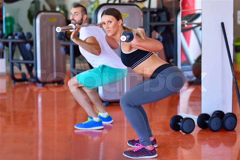 Gym man and woman push-up strength pushup with dumbbell in a workout, stock photo
