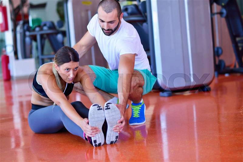 Young people involved in sports. Woman stretching with personal trainer, stock photo