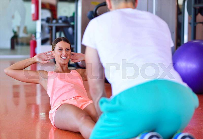 Personal trainer training a woman in the gym with yoga ball, stock photo