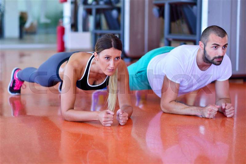 Photo of a woman doing pushups in a gym withe her personal trainer, stock photo