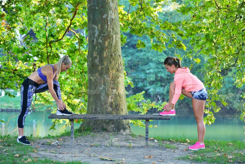 Runner girl tying laces shoes at the bench, stock photo