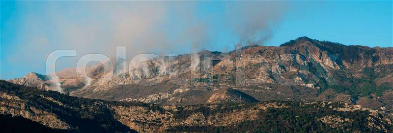 Fire in the mountains in the afternoon. Smoke over the mountains. Budva, Montenegro. Forest fires, stock photo