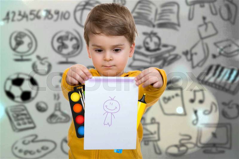 Little boy holding his first drawing in hands, stock photo