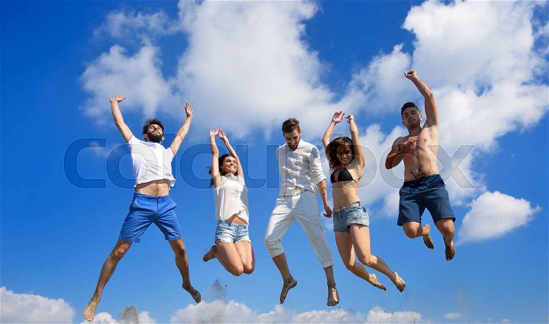Image of five energetic people jumping at the beach, stock photo