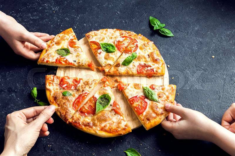 People Hands Taking Slices Of Pizza Margherita. Pizza Margarita and Hands close up over black background, stock photo