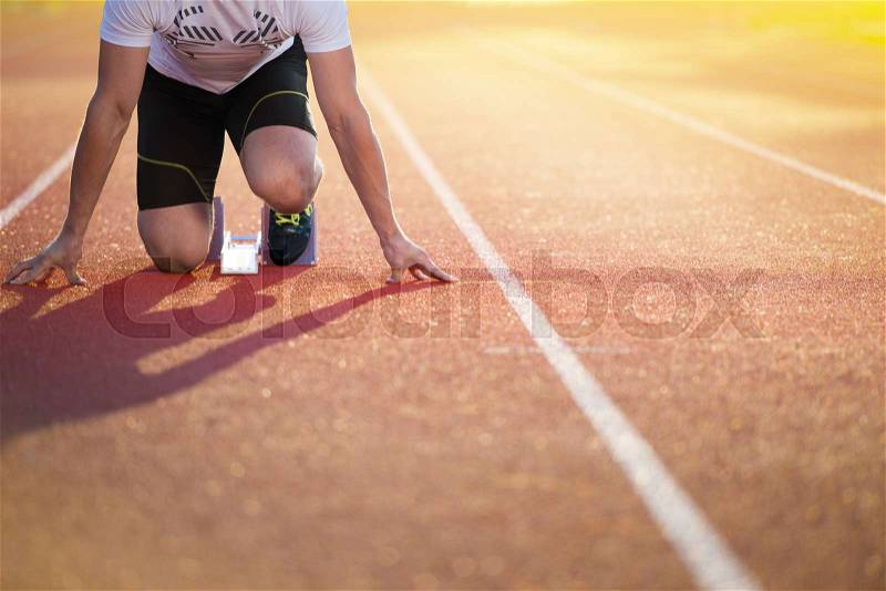 Athletic man on track starting to run. Healthy fitness concept with active lifestyle, stock photo