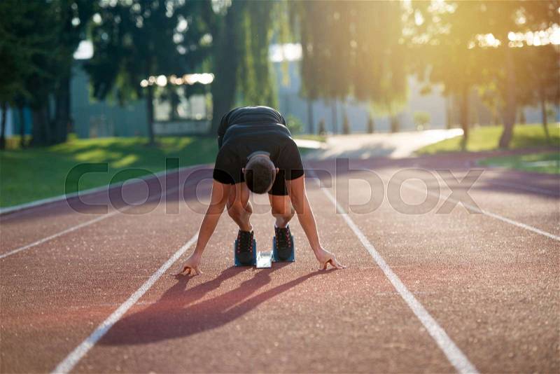 Athletic man on track starting to run. Healthy fitness concept with active lifestyle, stock photo