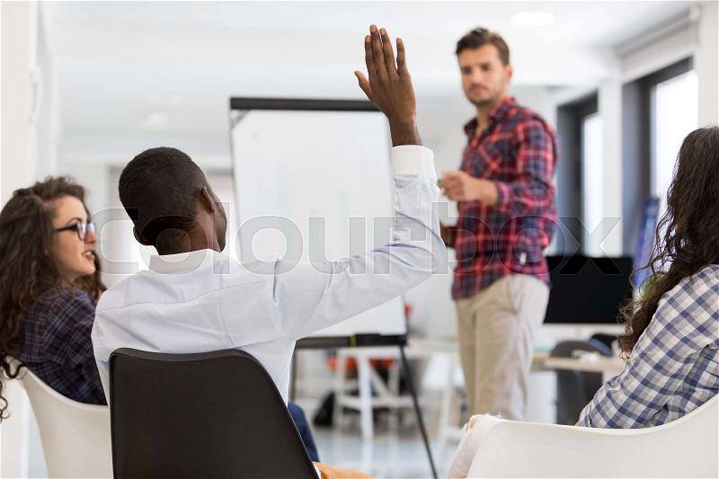 Businessman giving a presentation to his colleagues at work standing in front of a flipchart with notes and diagrams, stock photo