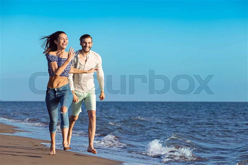 Happy couple running on the sand beach, stock photo