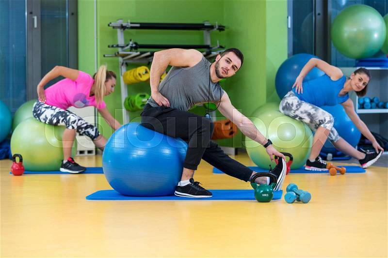 Portrait of happy group exercising on Swiss ball, stock photo