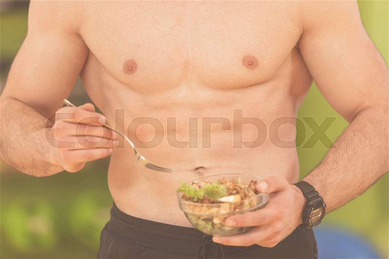 Shaped and healthy body building man holding a fresh salad bowl,shaped abdominal, stock photo