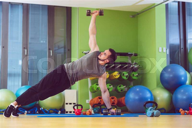 Young man lifting dumbbell at the fitness center, stock photo