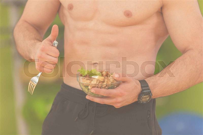 Shaped and healthy body building man holding a fresh salad bowl,shaped abdominal, stock photo