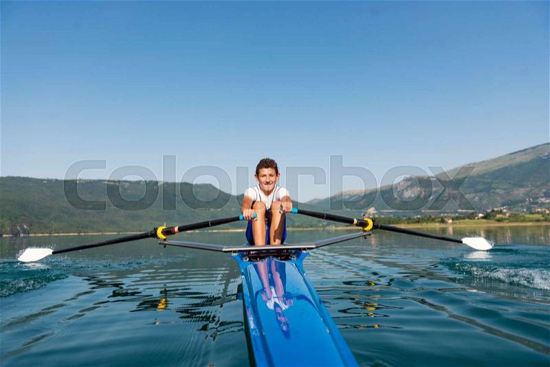 The young sportsman is rowing on the racing kayak, stock photo