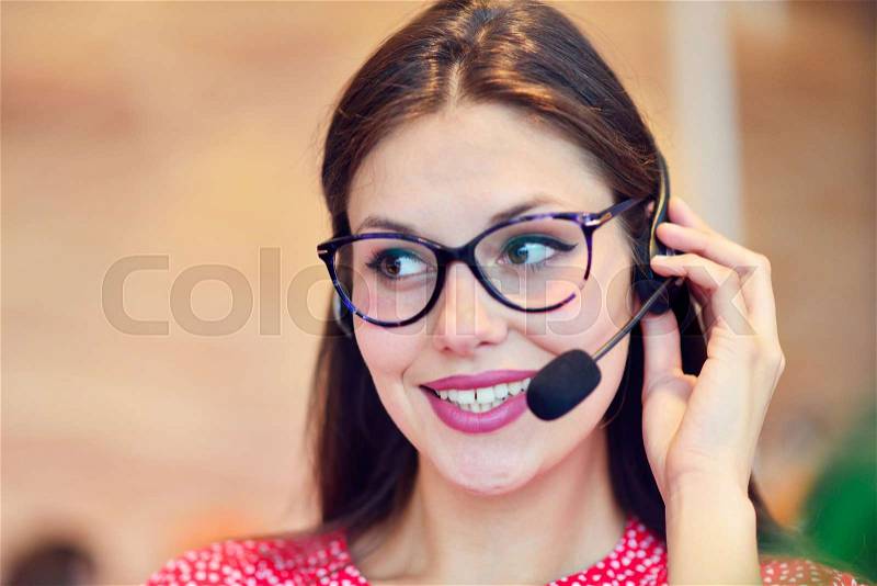 Female customer support operator with headset and smiling, stock photo
