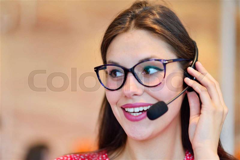 Female customer support operator with headset and smiling, stock photo