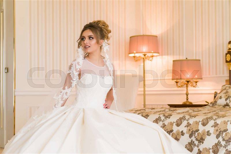 Portrait of beautiful young bride. A girl is posing in a hotel room. A lady Is worth with by the window. bride waiting in hotel, stock photo