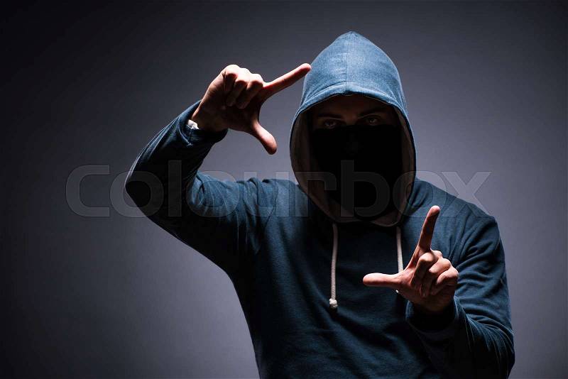 Man wearing hood in dark room, stock photo