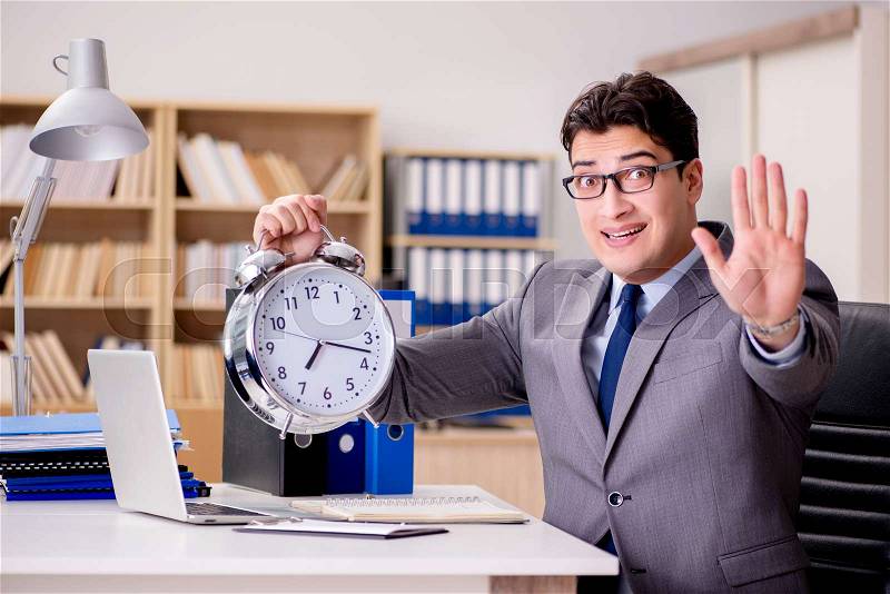 Businessman with clock failing to meet deadlines, stock photo