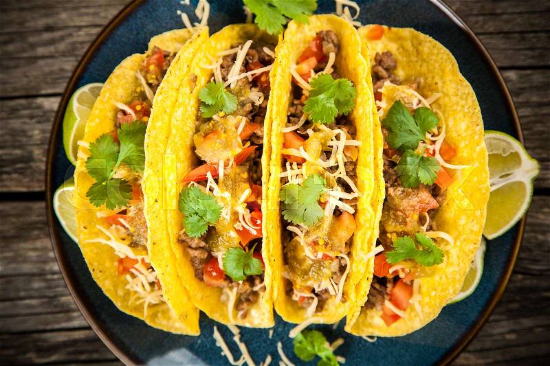 Mexican tacos with beef, cheese, tomato and green salsa, stock photo