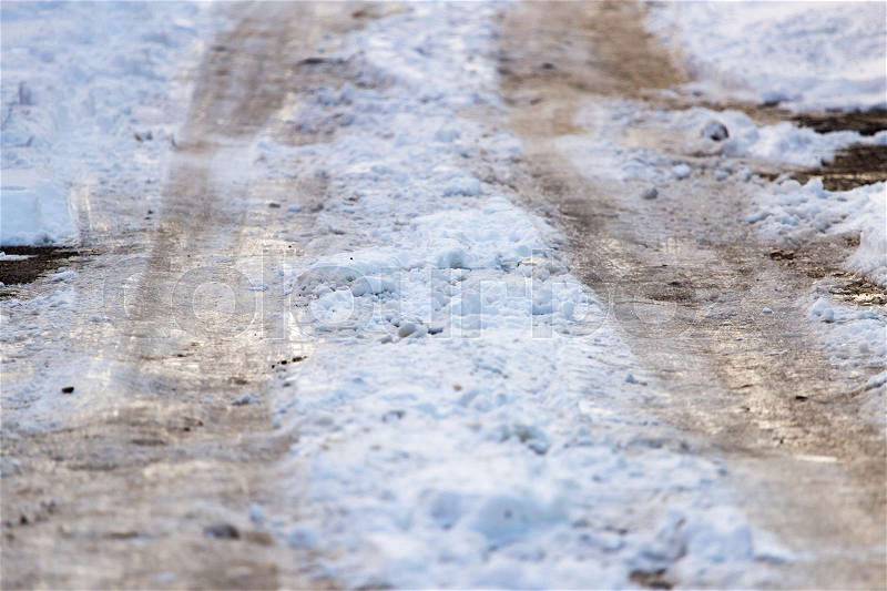 Snow with puddles on the road at sunset as background, stock photo