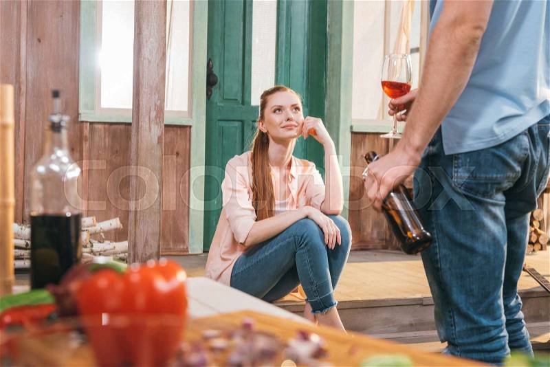 Attractive woman and man resting with beer and wine on porch, stock photo