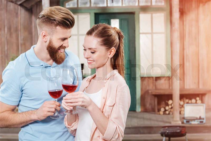 Happy man and woman embracing and holding wine in wineglasses, stock photo