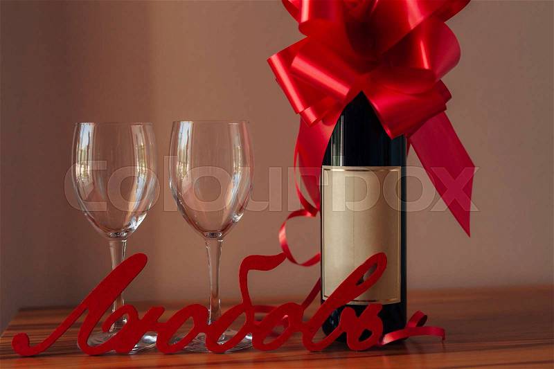 A bottle of champagne on the table and two empty glasses, a bottle tied with a red bow, stock photo