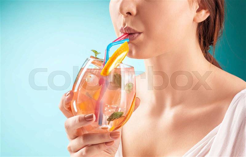 The pretty woman drinking cocktail. Emotion. Blue background, stock photo