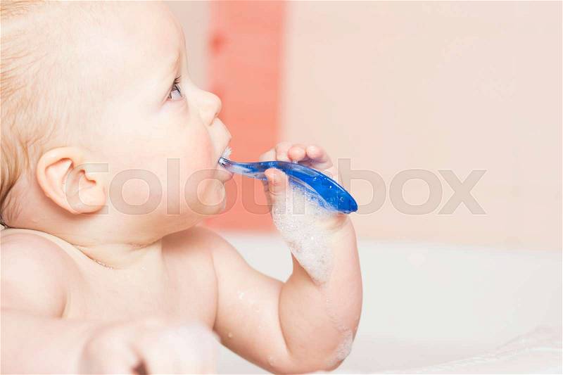 Funny baby boy brushes his teeth. Blue-eyed awesome inafnt kid brushin teeth first time. Close-up portrait, stock photo