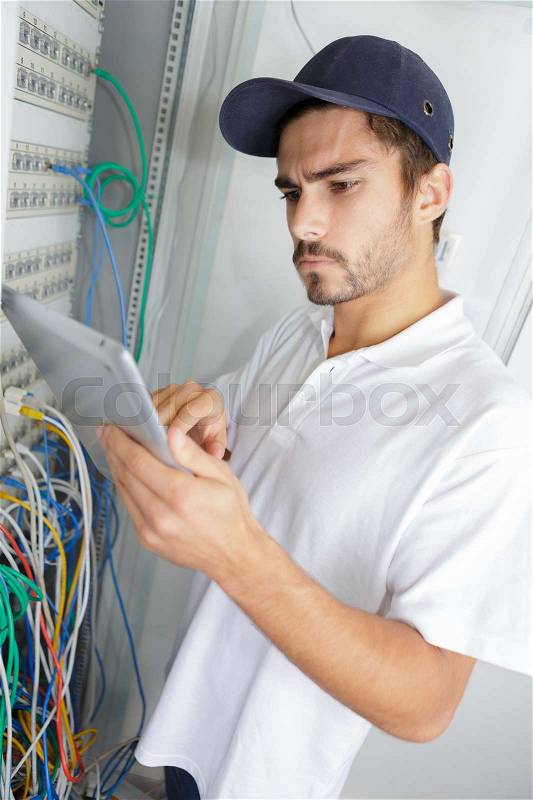 Focused electrician applying safety procedure while working on electrical panel, stock photo