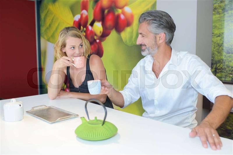 Seated man and lady with hot drinks, stock photo