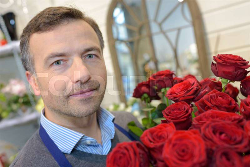 Portrait of male florist holding roses, stock photo