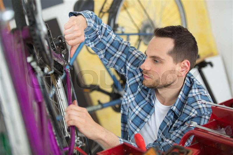 Man working on bicycle frame, stock photo