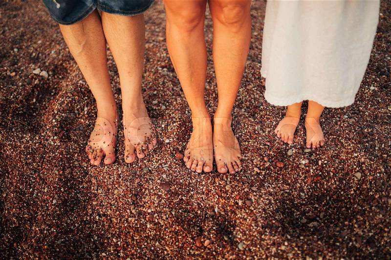 Children\'s legs and feet of parents. The family walks along the beach in Montenegro, stock photo
