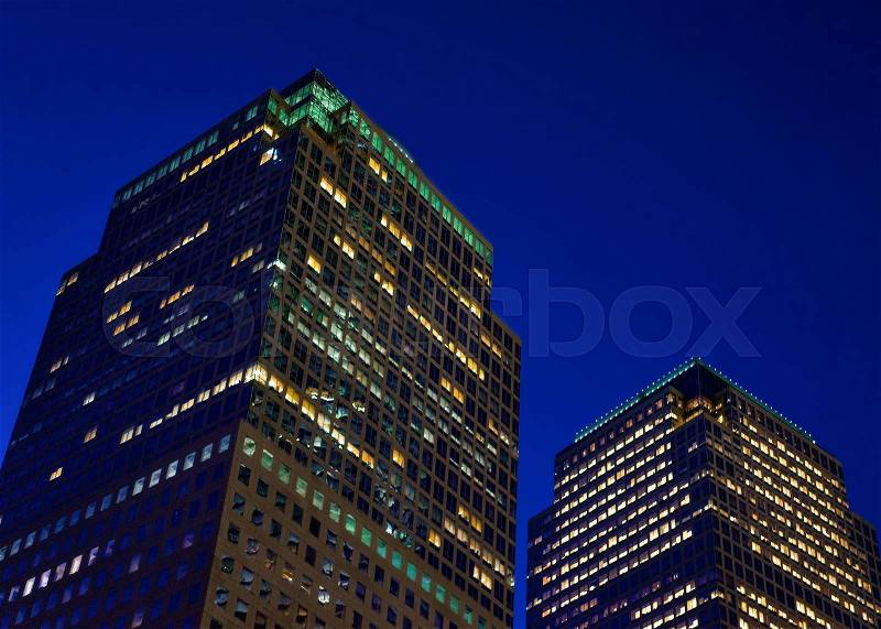 Bottom up view on glass skyscrapers in New York, USA. Illuminated with light late at night, stock photo