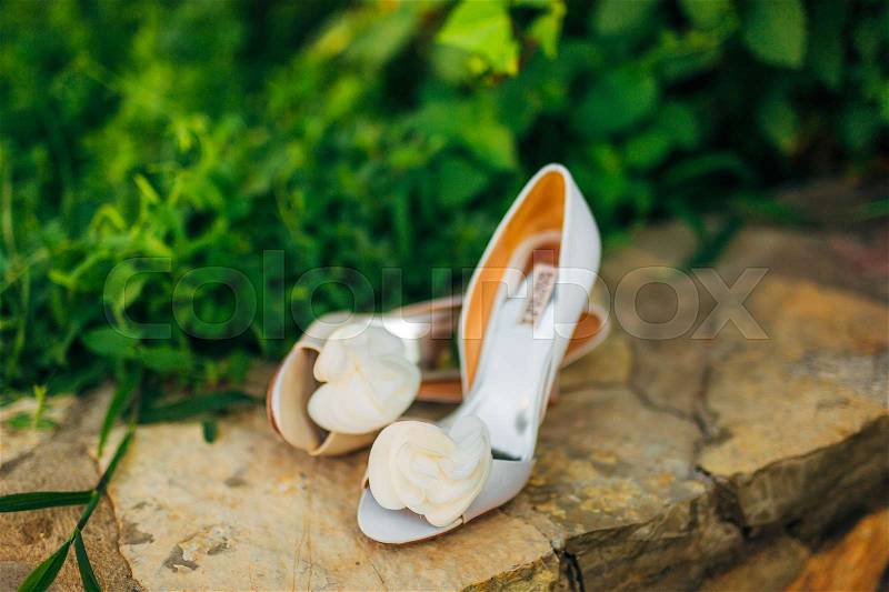 Wedding shoes on a stone border against a background of green leaves. Weddings in Montenegro, stock photo