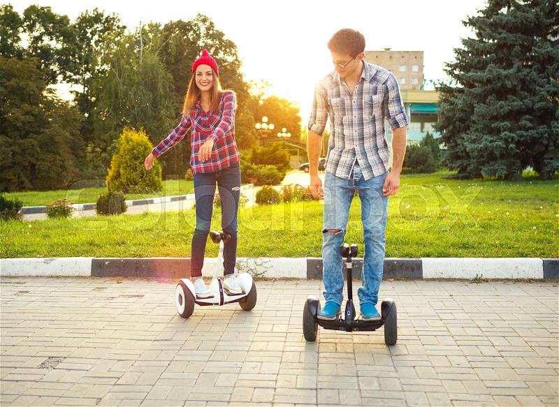Young couple riding hoverboard - electrical scooter, personal eco transport, gyro scooter, smart balance wheel. New modern technologies, stock photo