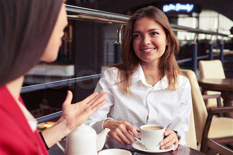 Close-up of marvelous businesswomen enjoying nice company and drinking coffee during lunch, stock photo