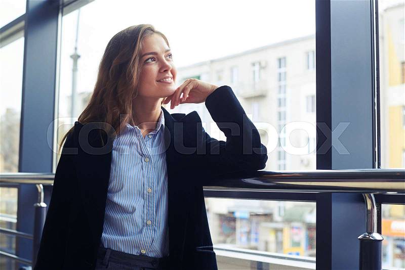 Low angle of romantic woman with loose hair looking through window. Female in formal clothes , stock photo