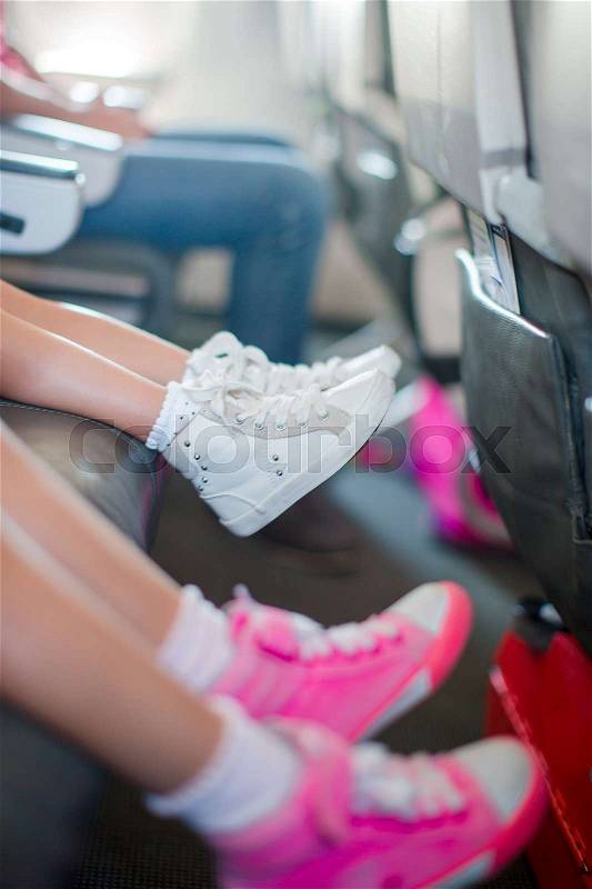 Baby feet in sneakers on seat in the aircraft Little adorable girls walking outdoors in flowers field, stock photo