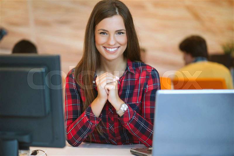 Concentrated at work. Young beautiful woman using her laptop while sitting in chair at her working place, stock photo