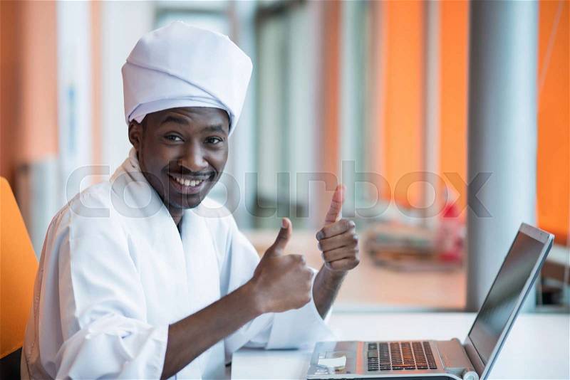Sudanese business man in traditional outfit using mobile phone in office, stock photo
