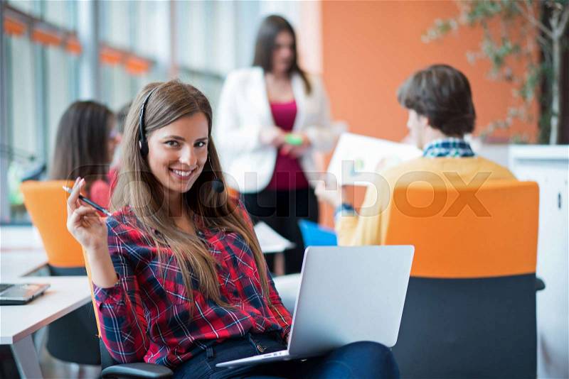 Happy young business woman with her staff, people group in background at modern bright office indoors, stock photo
