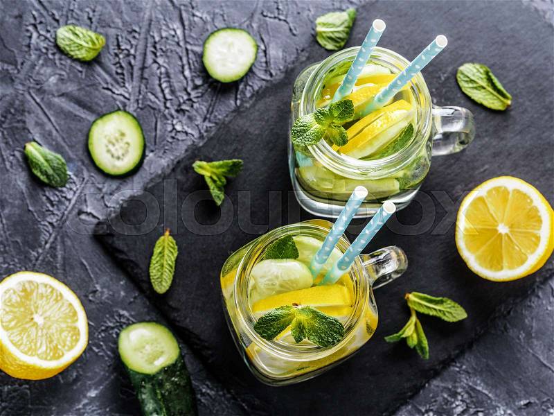 Above view of two mason jar with detox water on dark concrete background. Summer drink with cucumber, lemon and mint. Copy space. Top view or flat lay, stock photo