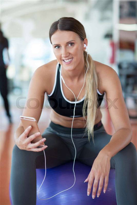 Woman setting music on smart phone putting earphones before exercise, stock photo