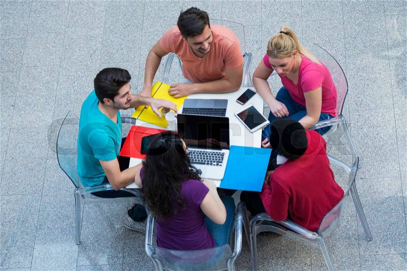 Multiracial group of young students studying together. High angle shot of young people sitting at the table and studying on laptop computer, stock photo