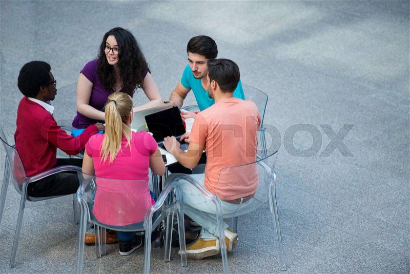 Multiracial group of young students studying together. High angle shot of young people sitting at the table and studying on laptop computer, stock photo