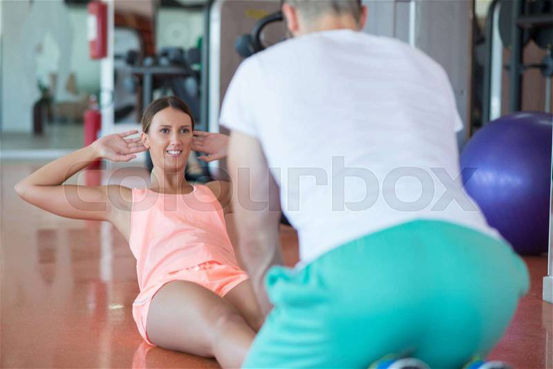 Personal trainer training a woman in the gym with yoga ball, stock photo