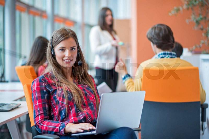 Happy young business woman with her staff, people group in background at modern bright office indoors, stock photo